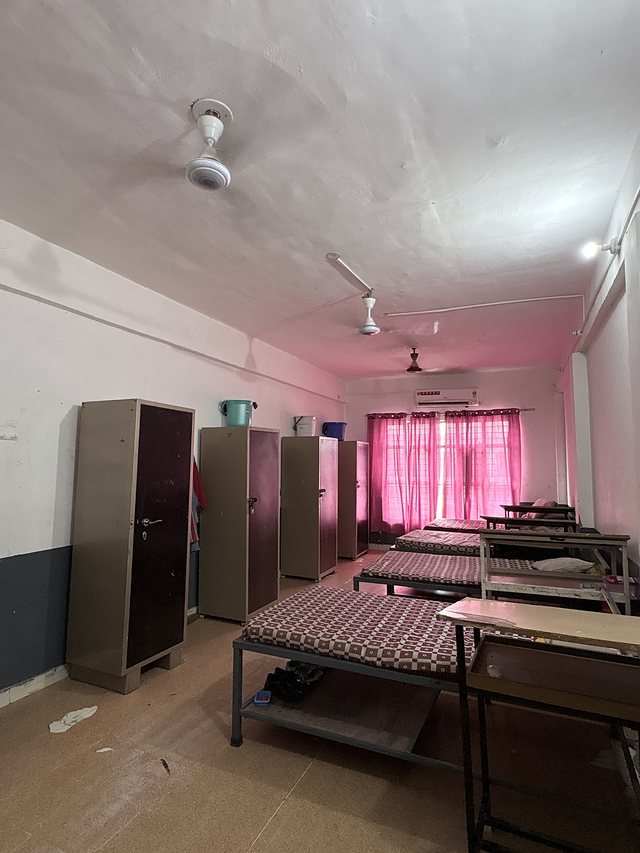 A hostel room with beds, lockers and storage trunks