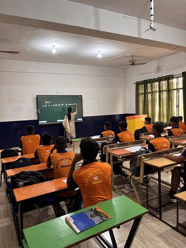 A teacher writing on the green board while the class works