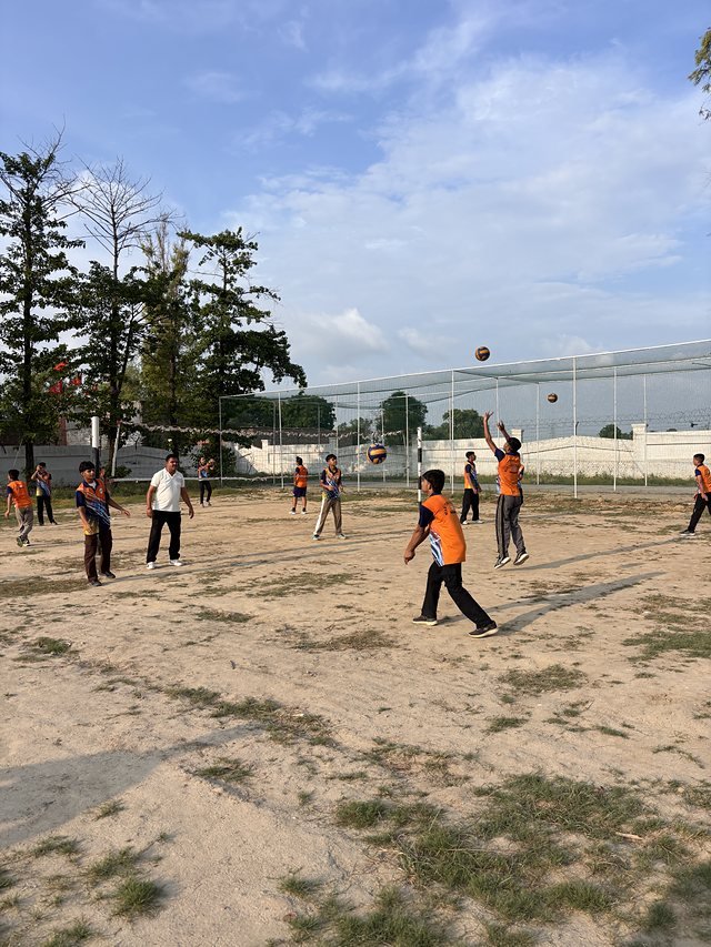 A volleyball rally with the ball in the air and both sides of the net in frame